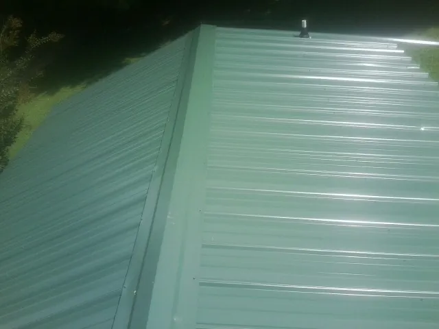 New green metal panels meeting at the ridge of a roof — Flat Roof Repair work by our crew in Jeffersonville